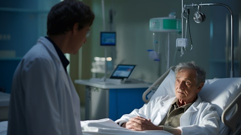 A medical professional in a lab coat, talking to an elderly patient in a hospital bed.