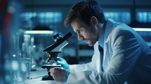 A scientist in a lab coat observing a sample under a microscope, illuminating the biopharmaceutical research undertaken by the company.