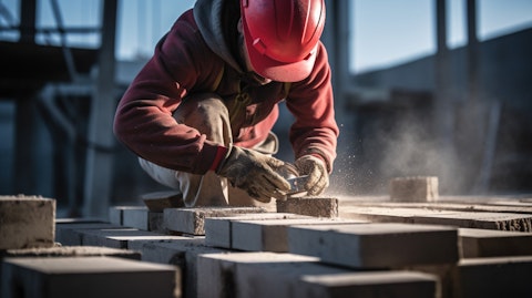 A worker on a construction site using specialized tools to connect concrete blocks. 