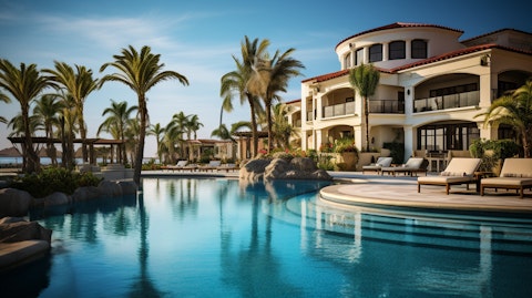 A luxurious resort hotel with a pool and beach in the backdrop.