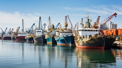 A line of dredgers and cranes at a marine transportation dock.