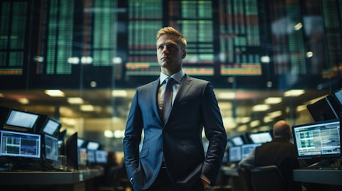 A well-dressed executive standing in front of a bank of sophisticated finance computers.
