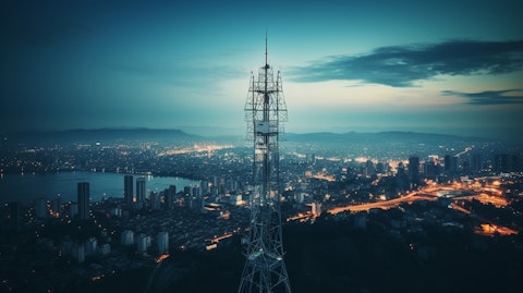 An aerial view of a communication tower against a backdrop of a city skyline.