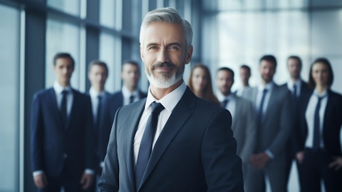 An executive in a suit flanked by workers, all smiling and looking confident.