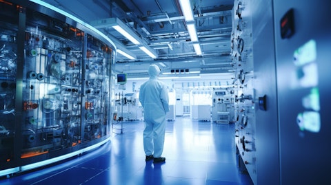A technician in a lab coat standing in a cleanroom with energy storage systems in the background.