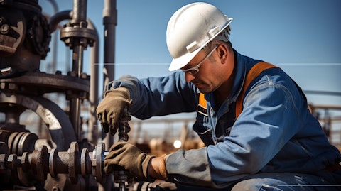 A technician in a jumpsuit working on a pumping system in an oil and gas well.