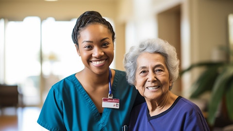 A nurse in scrubs, smiling while caring for a patient in a home health setting.