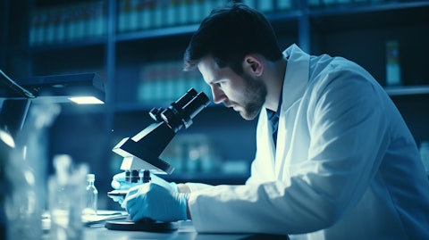 A scientist in lab coat testing a new biopharmaceutical drug on a microscope.