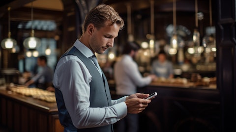 A business executive showcasing a mobile ordering app to a busy restaurant staff.
