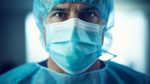 Closeup portrait of a surgeon wearing a surgical mask and gown while holding a surgical device.
