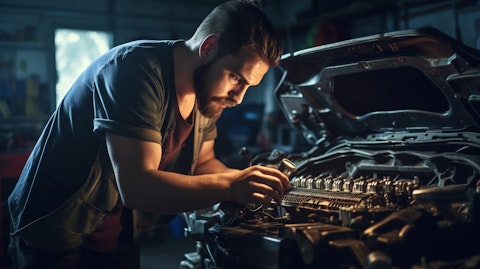 A garage mechanic working on a car engine, a bright light shinning on its components.
