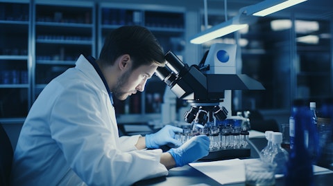 A research scientist studying cells through a microscope in a laboratory.
