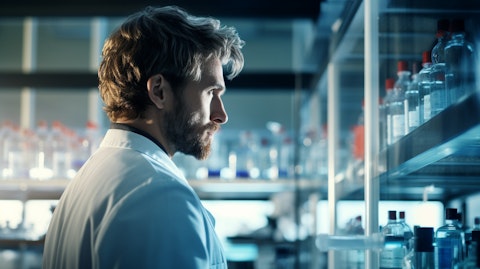 A technician in a lab looks off into the distance, showcasing the research taking place at Agios Pharmaceuticals.