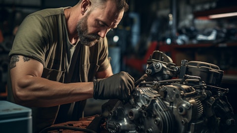 A mechanic in a workshop replacing a starter alternator with a new one.