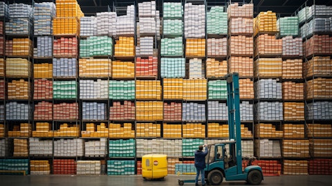 Large stacks of food containers in a warehouse with workers in the foreground.
