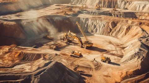 Aerial view of an open mine with large cranes and excavators working on the surface.