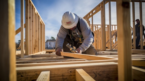 A worker hammering a nail into the frame of a single-family home under construction.