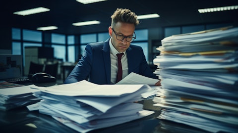A man in a suit flipping through a stack of financial documents on a trading desk.