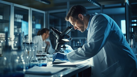 A laboratory researcher in a white coat, closely examining a microscope.
