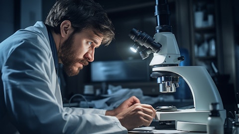 A doctor examining a patient’s eyes via microscope, while noting down their diagnosis.