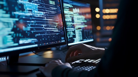 A close-up of a software programmer typing rapidly at a large monitor.