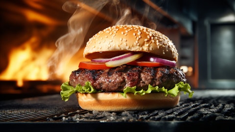 A close-up of a burger on a grill with steam rising in the background.