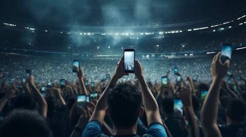 Huge crowds in a sports stadium with their smartphones streaming a live game.