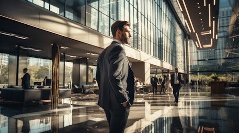 An executive in a sharp suit walking down the lobby of a towering corporate office building.