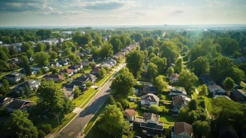 Aerial view of a city neighborhood with lush green and a line of homes in the foreground.