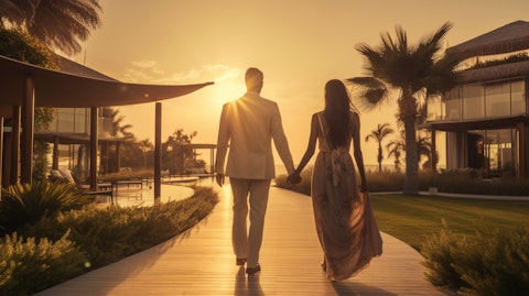 A couple entering a beach resort hotel, walking hand in hand away from the sunset.