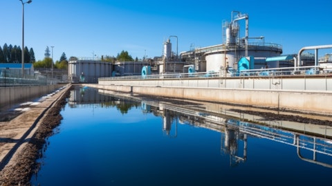 A treatment plant with a large industrial wastewater treatment pipe in the foreground.