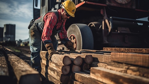 A worker in safety gear loading railroad ties on a truck, emphasizing the importance of manual labor.