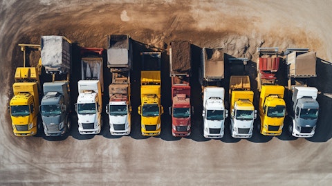 An overhead shot of a large fleet of trucks loaded with aggregate and construction material.