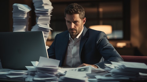 A close-up shot of a banker, looking confidently at his/her laptop, with stacks of papers and a toy credit card in the background.