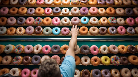An employee of the grocery store happily decorating doughnuts with colorful icing.