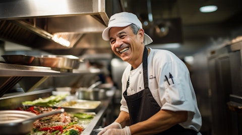A chef sharing a smile as he cooks up a customer's order at the kitchen station.