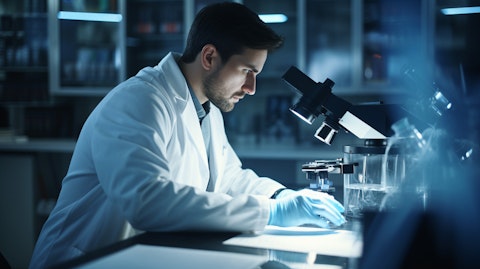 A scientist in a lab coat, using a microscope to study a sample of cells related to the company's biopharmaceuticals.