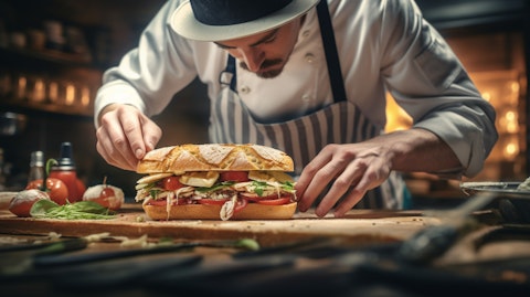 A chef in a busy kitchen, adding the finishing touches to a signature sandwich.
