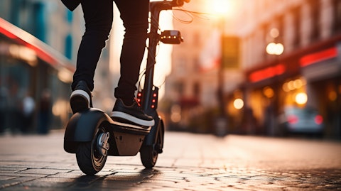 A close-up of a person riding a two-wheeled electric vehicle, against modern street backdrop.