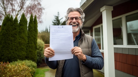 A homeowner happily smiling while holding a copy of their new insurance policy.