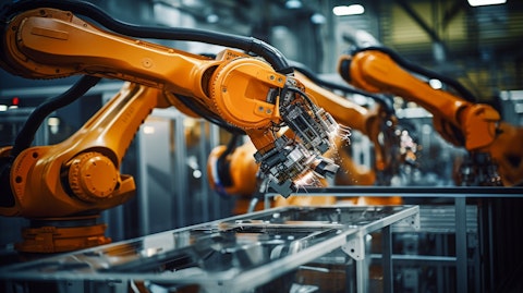 A close-up view of a robotic arm printing on an industrial manufacturing floor.