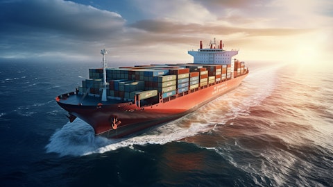 A large shipping container vessel with cranes in motion on the open sea.