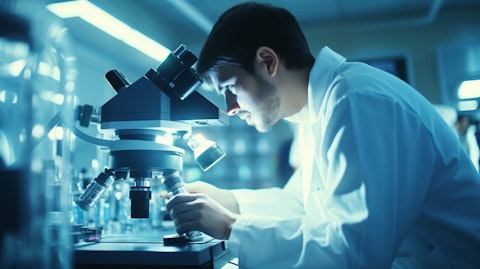 A scientist in a laboratory observing a drug delivery system through a microscope.