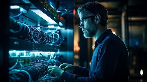 A technician observing a complex fiber-optic networking set-up in a laboratory.