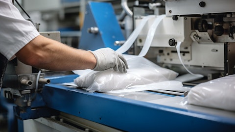 A close-up of a factory worker handling advanced plastics materials with specialized machinery.