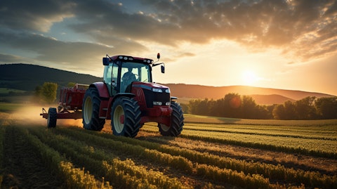 A farmer driving a tractor over his field with a picturesque backdrop of the setting sun.