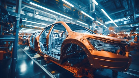 An auto plant production line full of workers assembling a car.