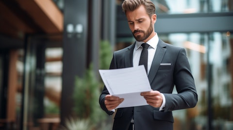 A business executive in a professional suit, holding a document in one hand with an authoritative expression.