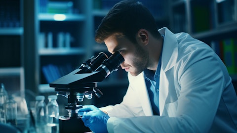 A medical researcher in a lab coat working with a microscope analyzing biology samples.