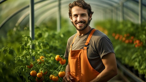 A farmer in overalls happily harvesting vegetables in a lush greenhouse.
